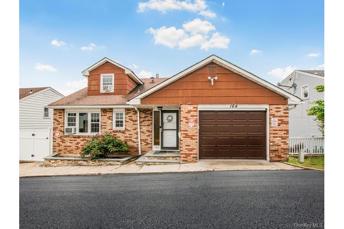 View of front of property with brick siding, an attached garage, asphalt driveway, and roof with shingles
