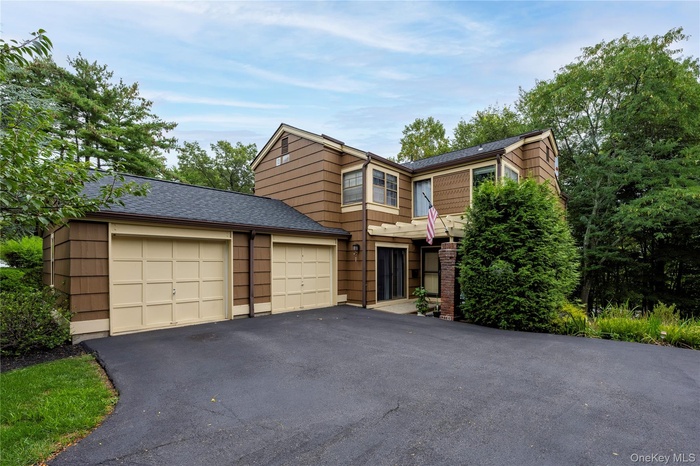 View of front of home featuring roof with shingles, an attached garage, and driveway