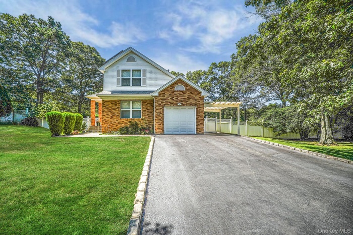 Traditional-style home featuring brick siding, driveway, an attached garage, and an attached carport