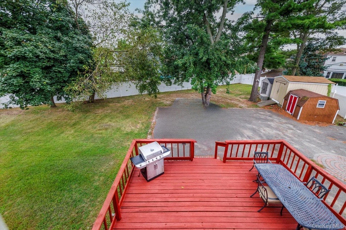 Wooden deck featuring a shed, a grill, and a fenced backyard