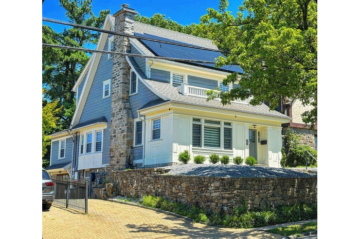 View of front of house featuring a chimney, board and batten siding, roof mounted solar panels, and a metal roof