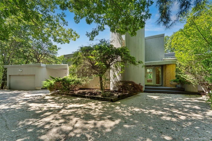 View of front facade featuring gravel driveway and a garage