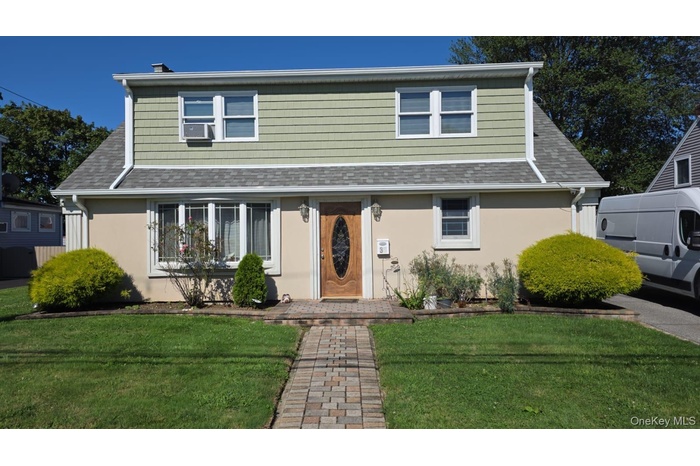 View of front of home with a front lawn, a shingled roof, and stucco siding