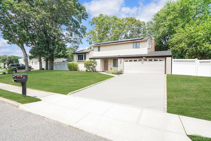 Split level home featuring roof mounted solar panels, concrete driveway, and a chimney