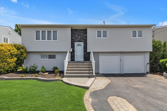 Split foyer home featuring an attached garage, asphalt driveway, and a front yard