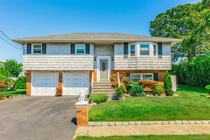 Split foyer home with brick siding, an attached garage, a front lawn, and asphalt driveway
