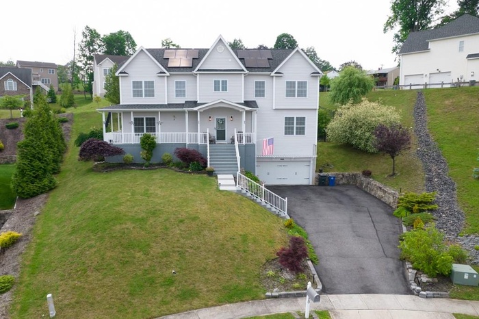 View of front of property with a porch, a front lawn, roof mounted solar panels, stairway, and an attached garage