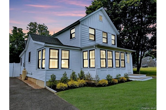 View of front facade featuring driveway, a front yard, and board and batten siding