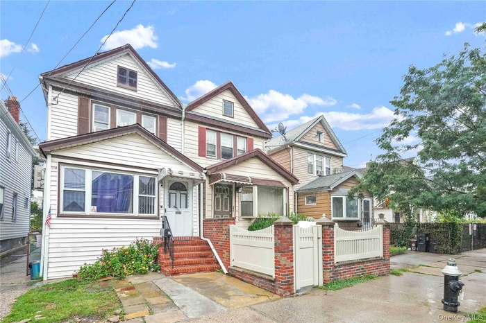 View of front of house with a fenced front yard, a gate, and brick siding