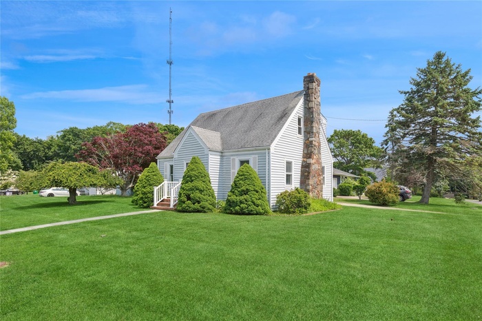 View of side of property with a yard, a chimney, and a shingled roof