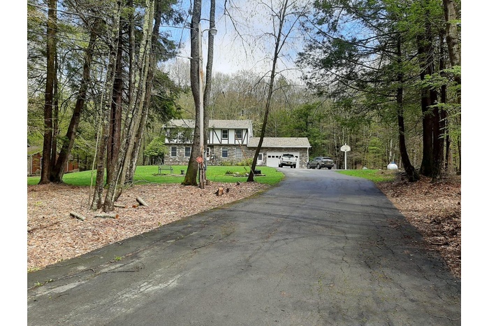 View of front facade with a garage, stone siding, and a front lawn