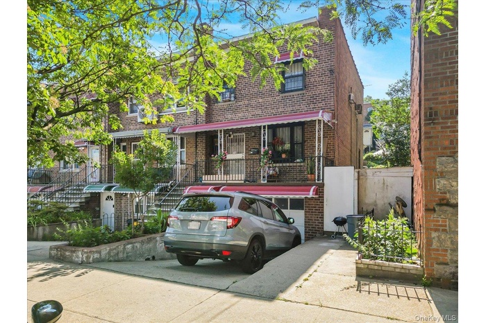 View of front of house featuring brick siding, concrete driveway, a garage, and stairs