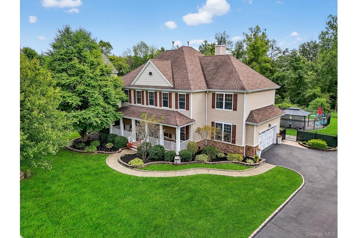 View of front of property with a porch, driveway, a shingled roof, a chimney, and stone siding