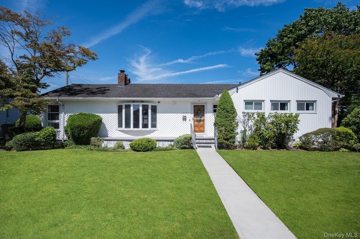 Ranch-style house featuring a front yard, a chimney, and a shingled roof