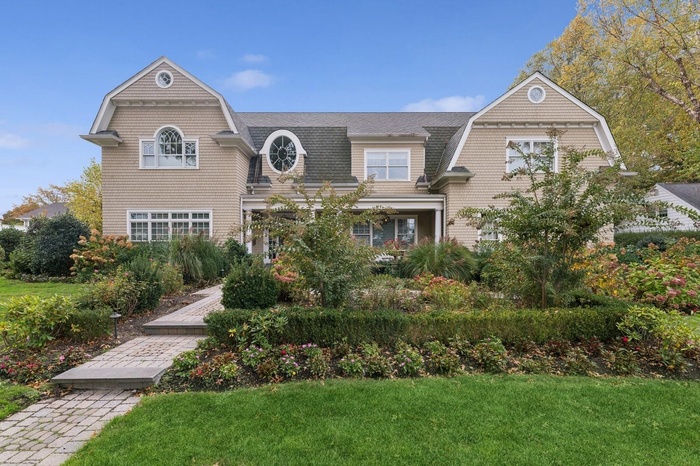 Shingle-style home with a gambrel roof, a shingled roof, and a front lawn