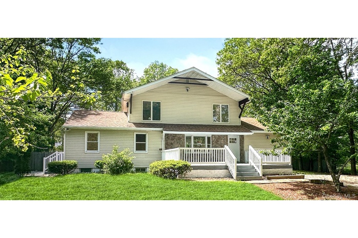 View of front of home with a front yard, a shingled roof, and a wooden deck
