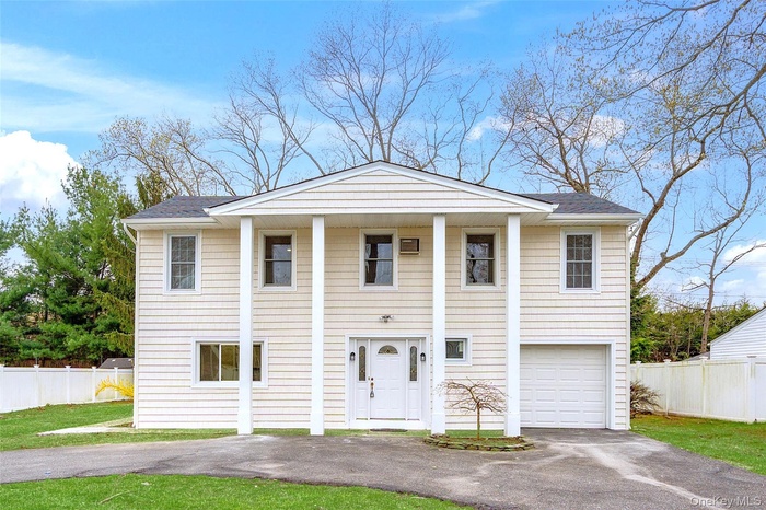 View of front of property featuring driveway, a garage, and roof with shingles