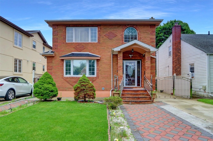 View of front facade with brick siding, a gate, and a front lawn