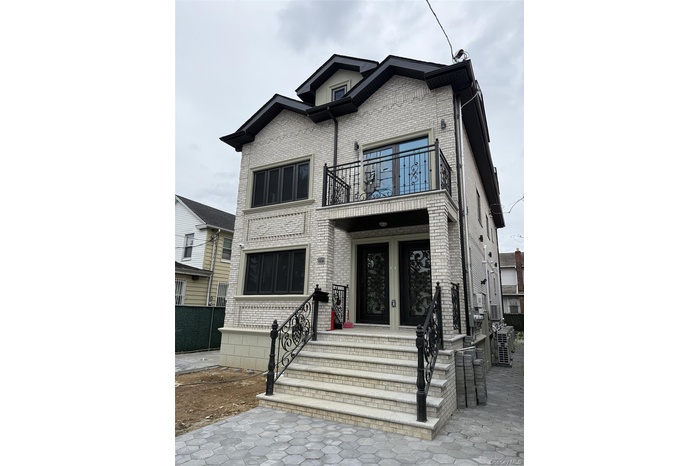 View of front of house with a balcony and brick siding