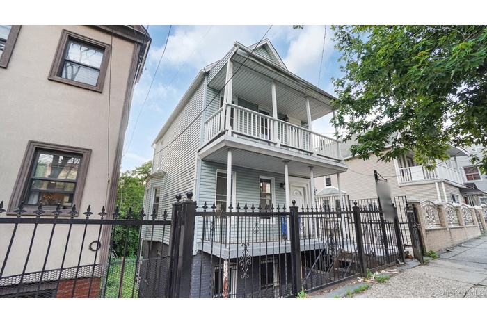View of front of property with a fenced front yard, a gate, and a balcony