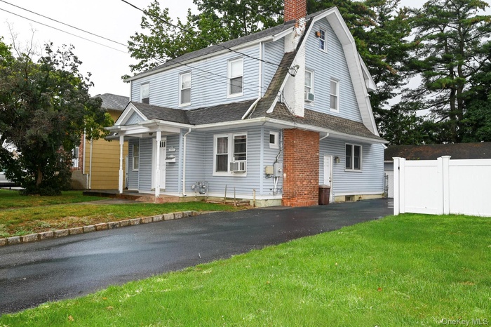 Colonial inspired home with a gambrel roof, roof with shingles, and a chimney