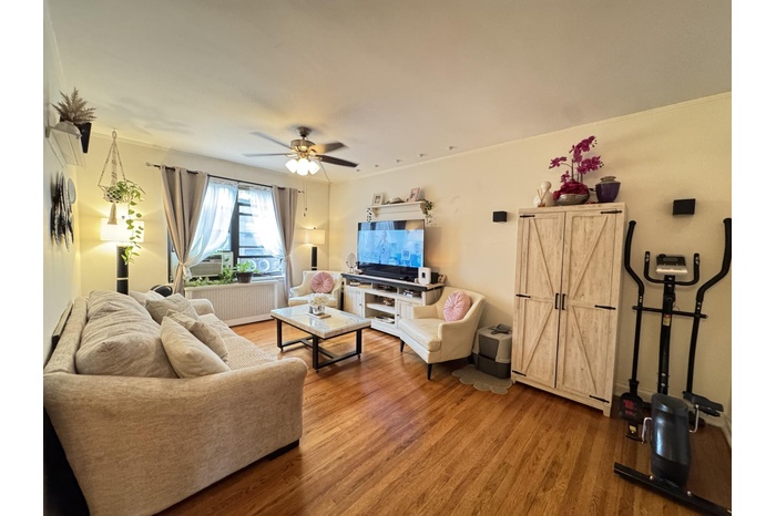 Living room featuring wood finished floors, radiator heating unit, and a ceiling fan