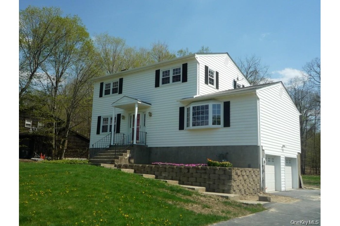 Colonial house featuring a garage, a front yard, and driveway
