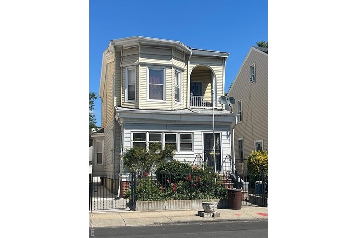 View of front of property with a fenced front yard and a balcony