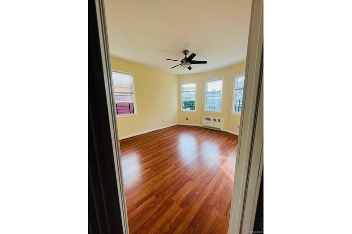 Unfurnished room featuring light wood-style floors, radiator, and a ceiling fan