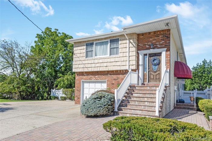 View of front of home with decorative driveway, brick siding, and a garage