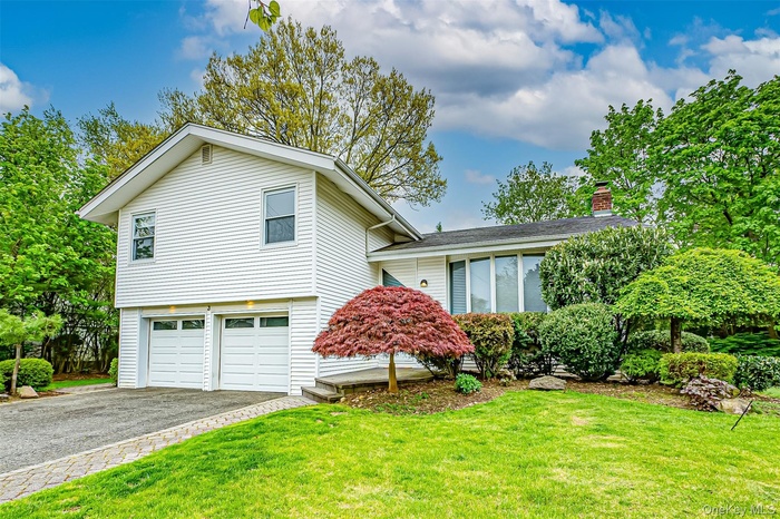 View of front facade featuring a front yard and a garage