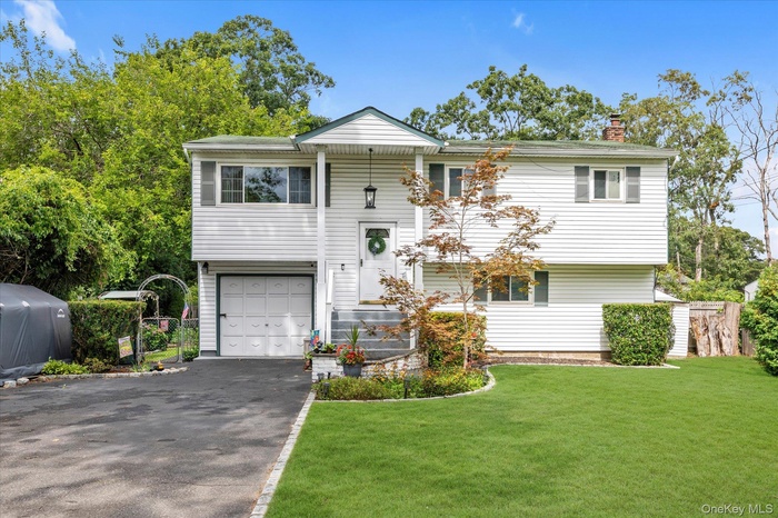 Bi-level home with a garage, driveway, and a chimney
