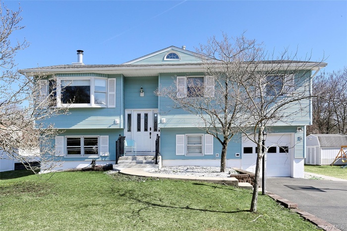 Bi-level home with a front yard, an attached garage, and asphalt driveway