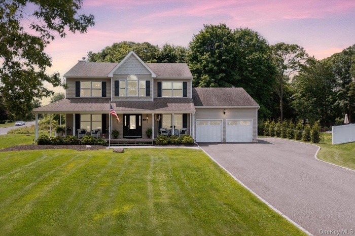 View of front of home with covered porch, a garage, asphalt driveway, and a yard