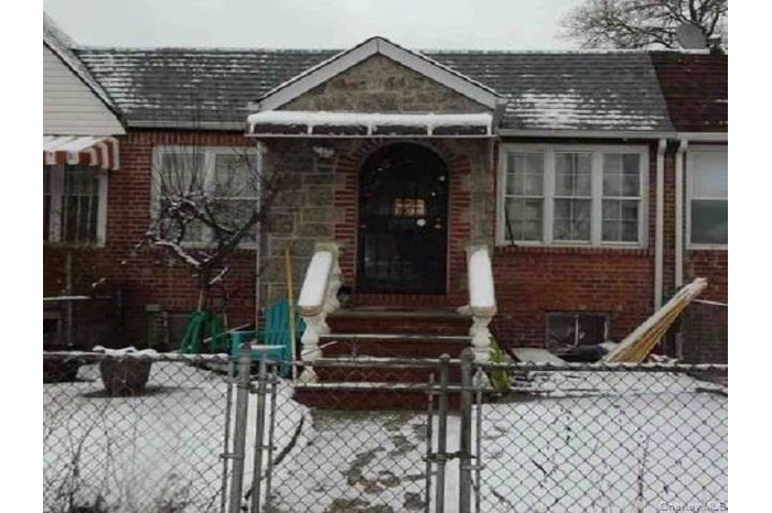 View of front of property with a fenced front yard, a gate, a shingled roof, and brick siding
