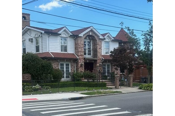 Traditional-style home featuring a fenced front yard, french doors, an AC wall unit, and brick siding