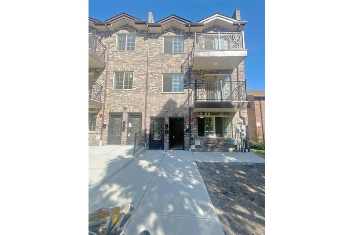 View of front of house featuring a balcony, a chimney, and brick siding