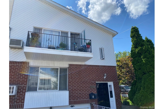 View of side of home featuring a balcony and brick siding