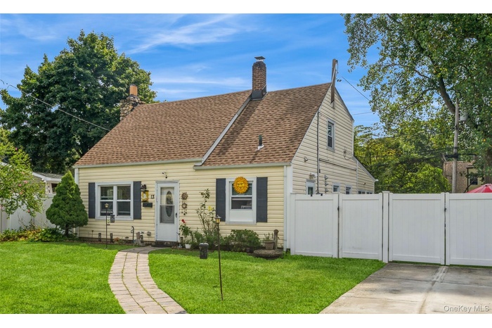 View of front of home with a gate, a shingled roof, and a chimney