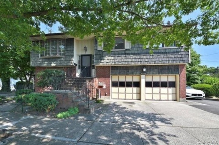 Split foyer home featuring a garage, driveway, and brick siding