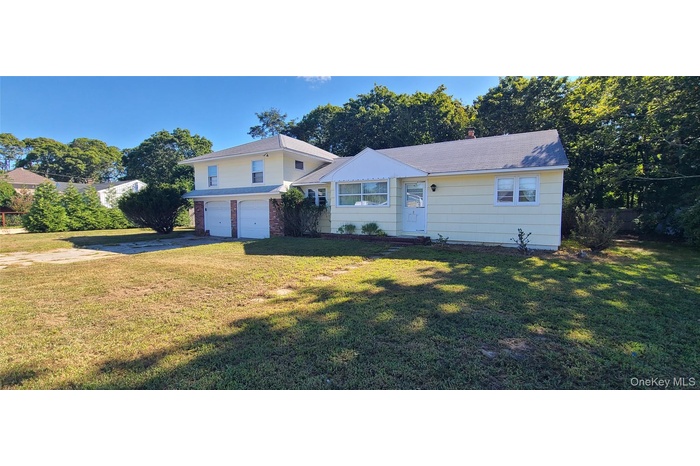 View of front of house featuring concrete driveway, an attached garage, and a front yard