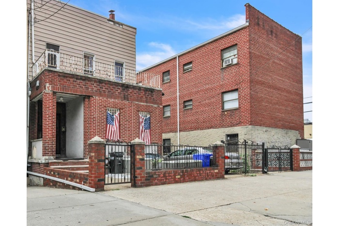 View of building exterior featuring a balcony and fenced front yard.