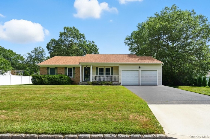 Ranch-style house featuring covered porch, a garage, driveway, and brick siding
