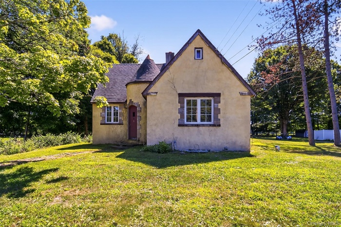 View of front facade with a front lawn and stucco siding