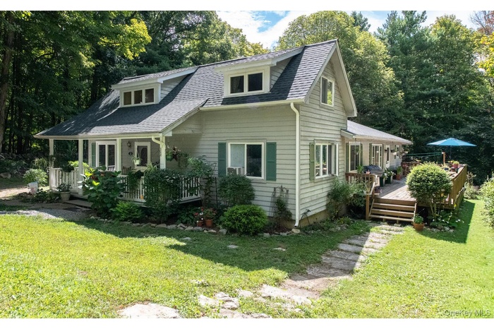 View of front of property with a front yard, a shingled roof, and a deck