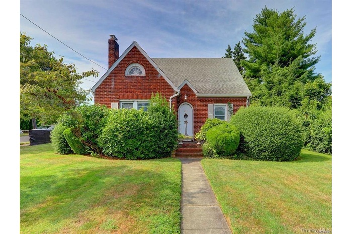 View of front of home with a front yard, a chimney, and brick siding