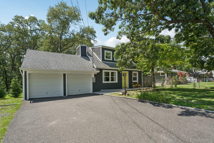 View of front of property featuring roof with shingles, an attached garage, asphalt driveway, and a chimney