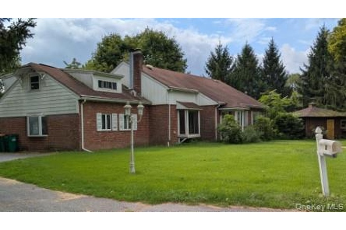 Front of house with a lawn, brick, and a chimney