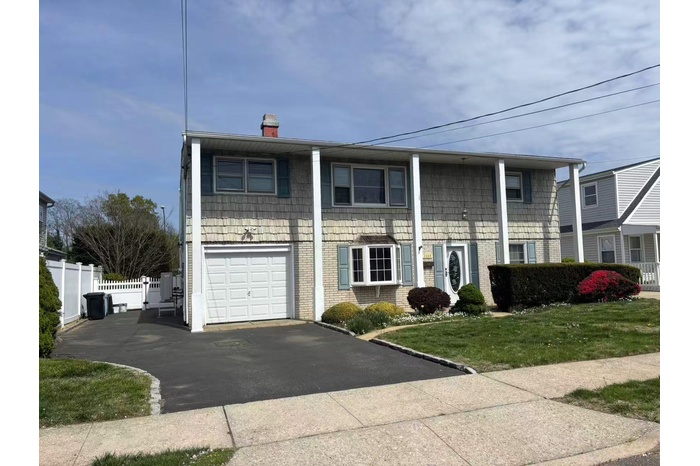 View of front of home featuring a chimney, driveway, a garage, and brick siding