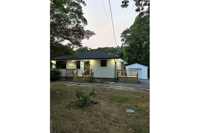 View of front of house with an outbuilding, a chimney, a garage, board and batten siding, and a deck